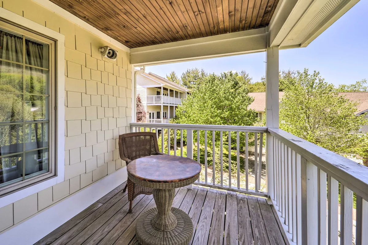 A tranquil exterior scene with a wicker chair and a small round table, set against lush greenery. Designed for sipping coffee, reading, or simply enjoying the view, this space feels private and serene.