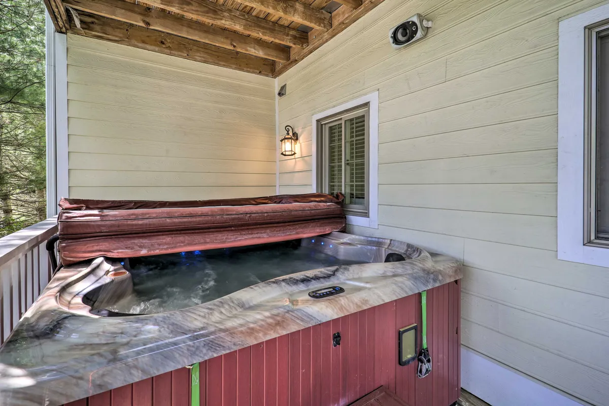 The image features a private hot tub set on a deck with wooden beams, illuminated by warm lantern light. The ambiance is tranquil and inviting, with the hot tub positioned to offer views of the surrounding natural landscape, perfect for stargazing or unwinding with loved ones.