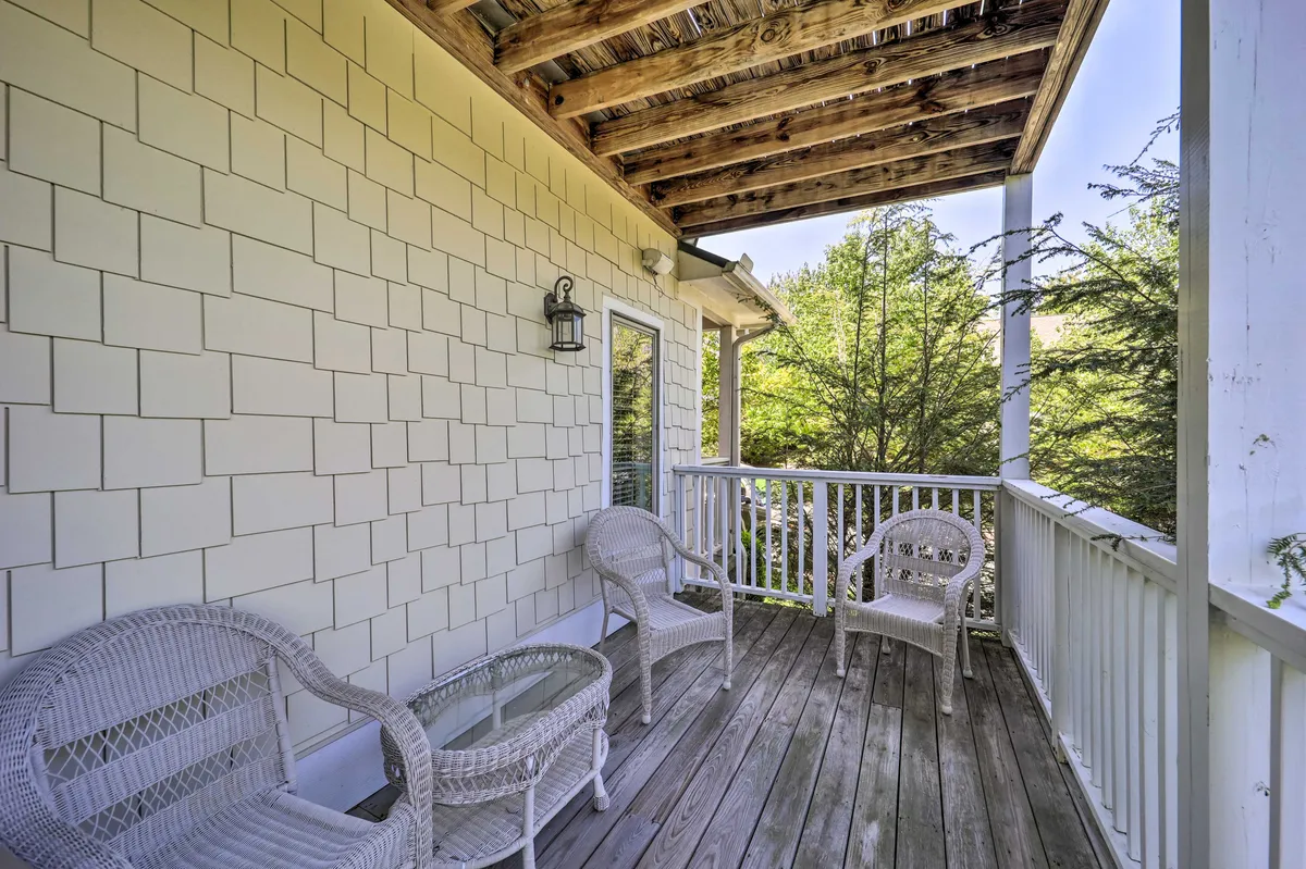 A cozy outdoor sitting area with wicker chairs, a glass table, wooden beams, and lush greenery all around. The ambiance is suited for morning coffee, afternoon reading, or evening conversations, tying into the family-friendly and communal atmosphere described in the section.