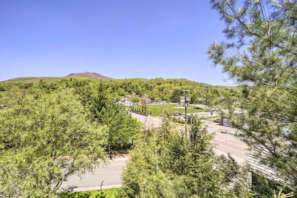 A sweeping view of the surrounding mountains, lush green foliage, and an open space ideal for outdoor exploration. The scene captures the beauty and tranquility of the natural environment, making it perfect for hiking, picnicking, or simply soaking in the scenery.