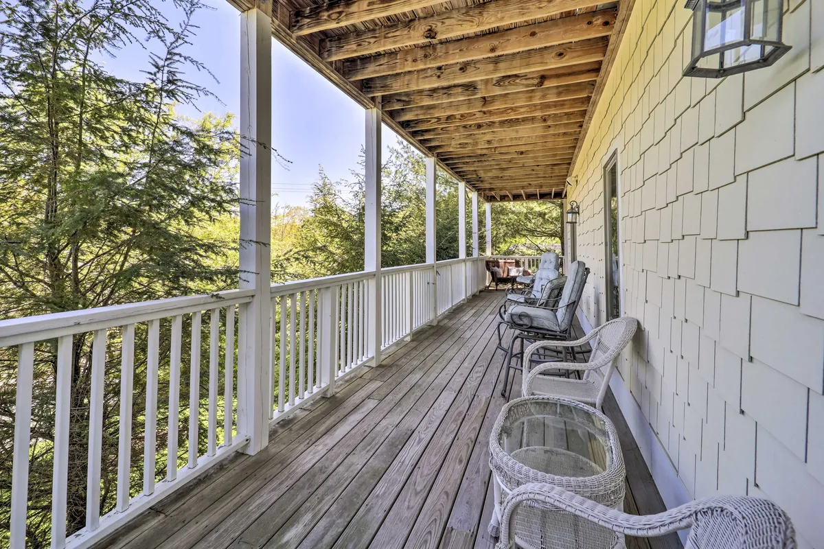 A spacious wooden deck with classic rocking chairs set against a backdrop of lush greenery. The deck offers a cozy space to relax, socialize, and enjoy the outdoors, inviting guests to step outside and savor the peaceful mountain environment just a short walk from downtown Banner Elk.